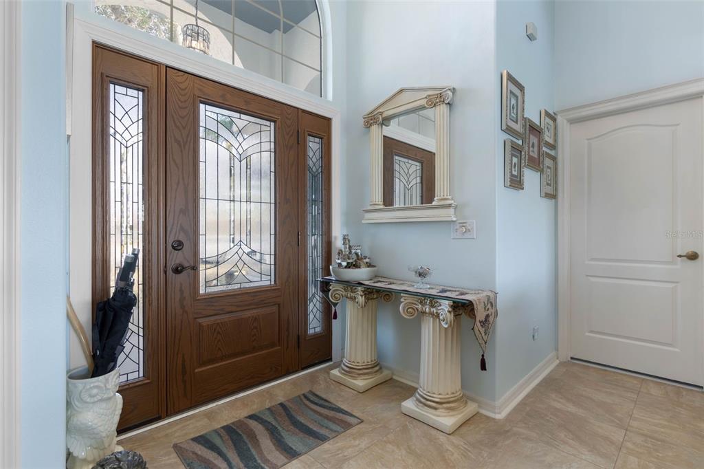 A foyer features a wooden front door with glass panels, a console table, and tile flooring — 10 CHELSEA COURT, PALM COAST, FL