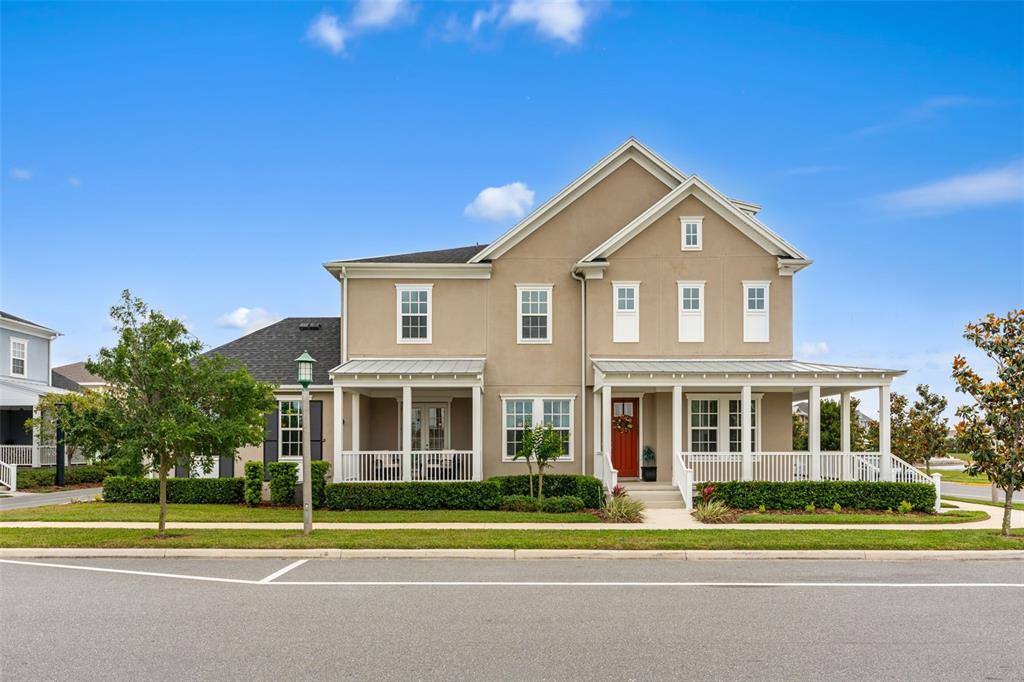 A two-story tan house with a covered front porch and a red front door — 1851 COASTAL COURT, CELEBRATION, FL