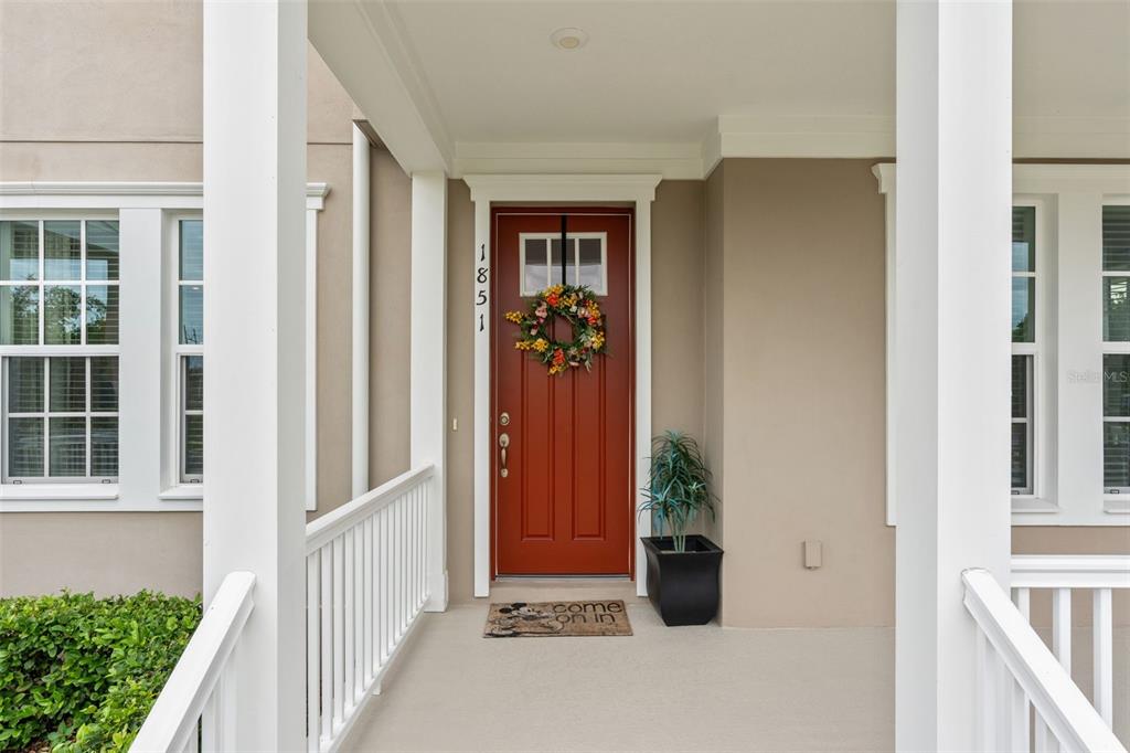 A two-story house with a wrap-around porch and a red front door at sunset — 1851 COASTAL COURT, CELEBRATION, FL