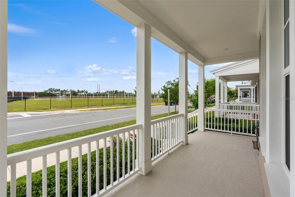 A red front door with a wreath and house numbers sits on a covered porch — 1851 COASTAL COURT, CELEBRATION, FL