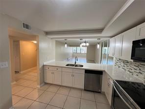 A kitchen with white cabinets, stainless steel appliances, and a pass-through window to the living area — 8040 Hampton Boulevard # 104, North Lauderdale FL 33068, NORTH LAUDERDALE, FL