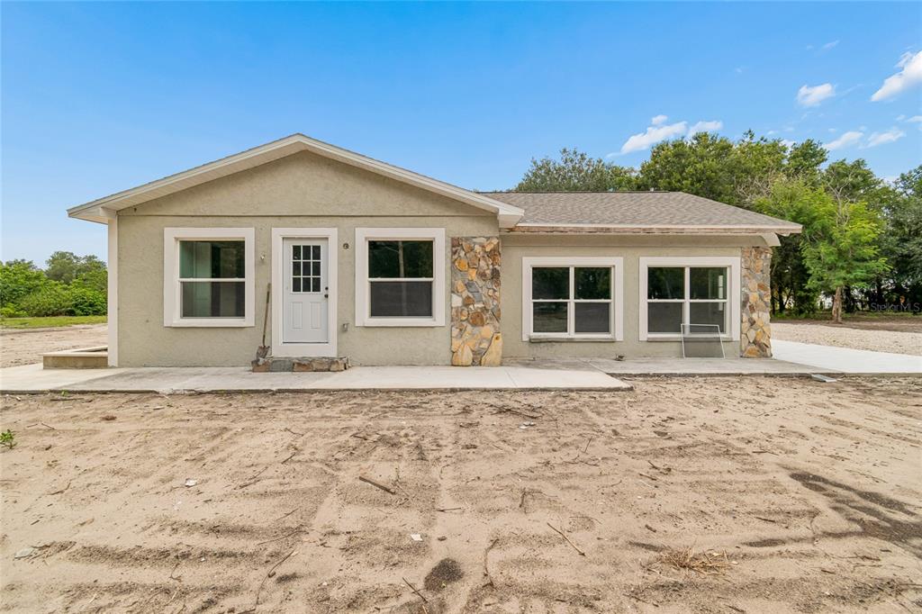 A single-story house with a stucco exterior, stone accents, and a concrete patio — 15628 CARLTON LAKE ROAD, WIMAUMA, FL