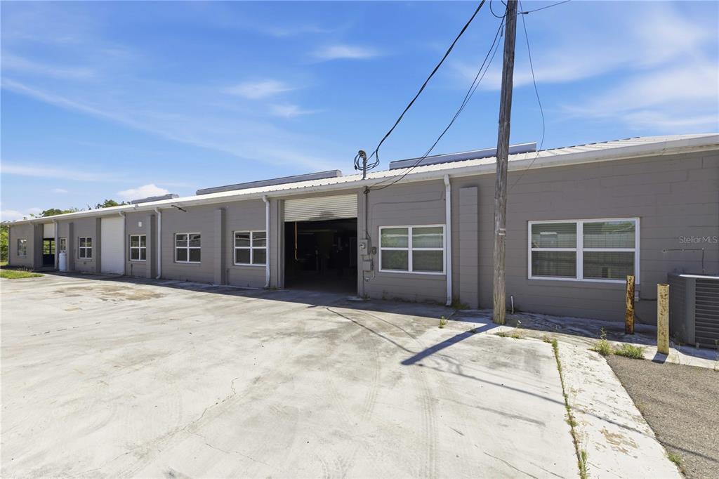 A gray, single-story industrial building features multiple windows and a large open roll-up door — 943 NW 17TH AVENUE, OCALA, FL