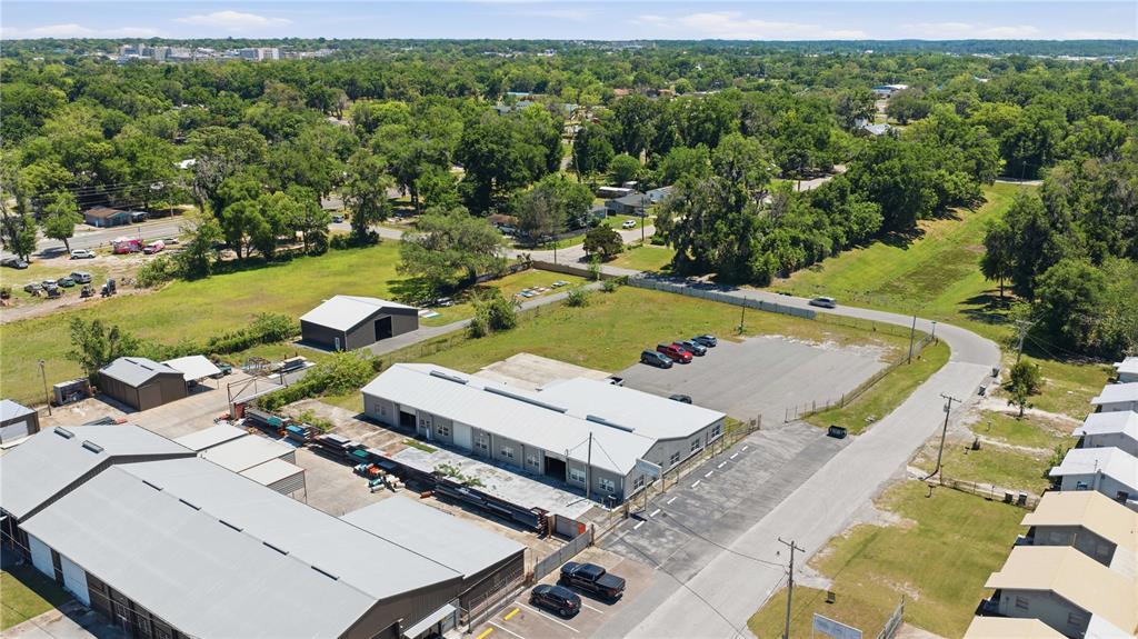 An aerial view shows industrial buildings with metal roofs, a parking lot, and surrounding trees — 943 NW 17TH AVENUE, OCALA, FL