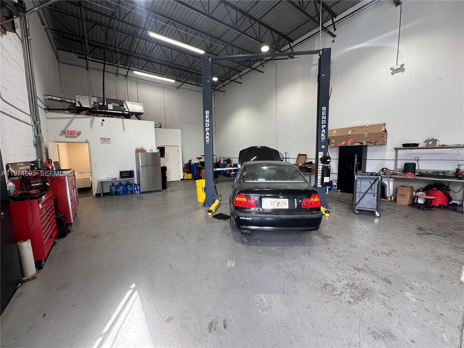 A commercial auto repair shop features a two-post car lift and a black sedan — 3136 John P Curci Dr, Hallandale Beach FL 33009, HALLANDALE BEACH, FL