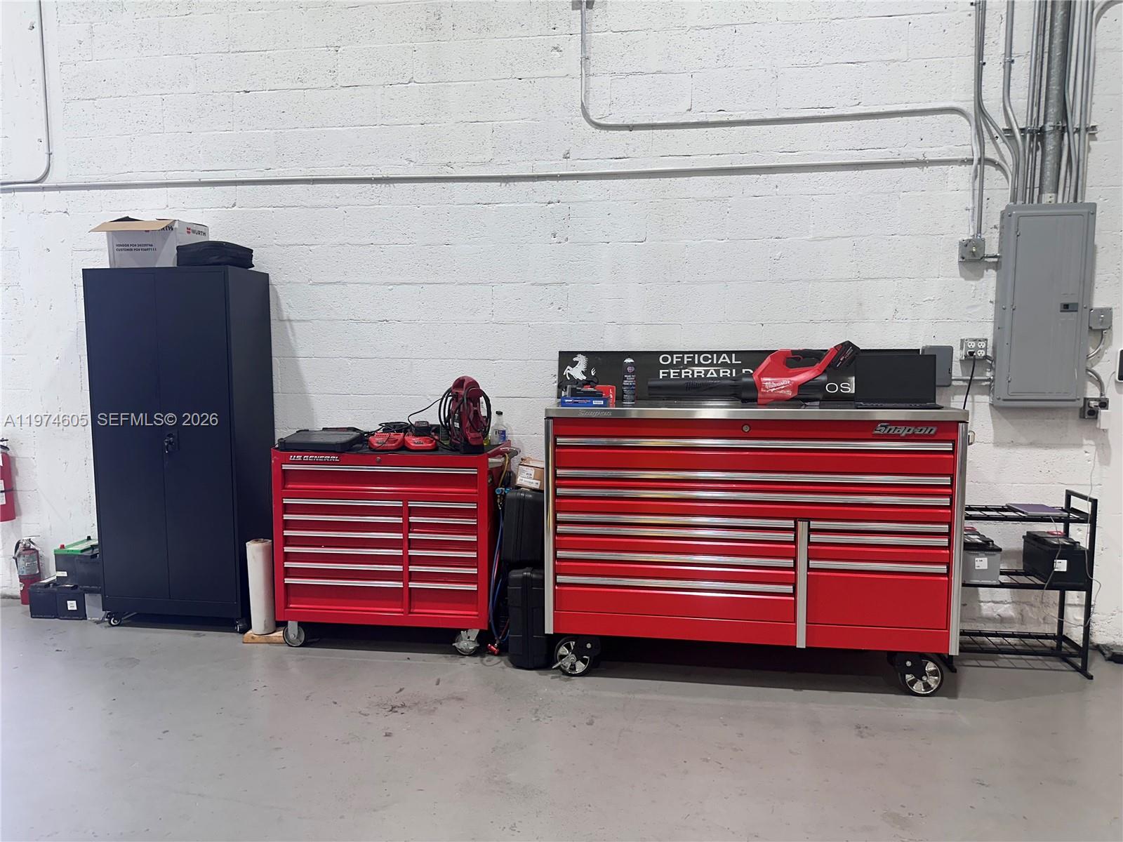 A garage workspace features a tall black cabinet and two red tool chests against a wall — 3136 John P Curci Dr, Hallandale Beach FL 33009, HALLANDALE BEACH, FL