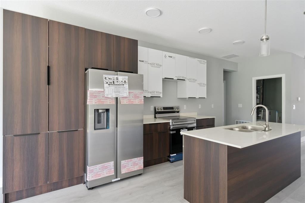 A modern kitchen features dark wood cabinetry, stainless steel appliances, and a white quartz island — 397 NORTH BOULEVARD W, DAVENPORT, FL