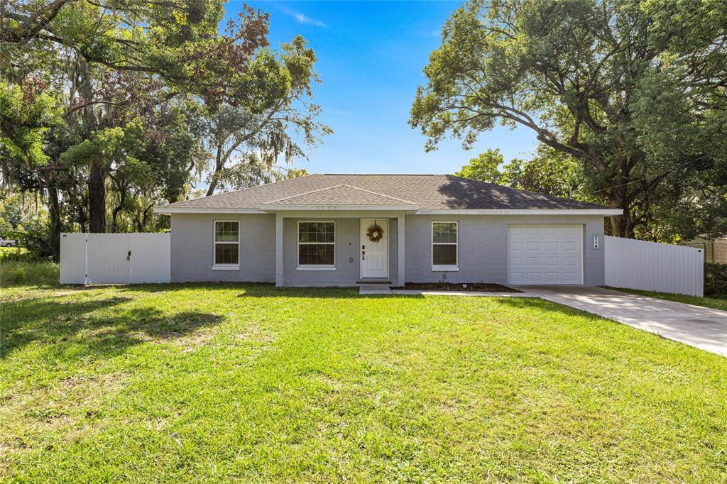 A single-story gray house with a white garage door and a white vinyl fence — 714 NW 1ST STREET, OCALA, FL