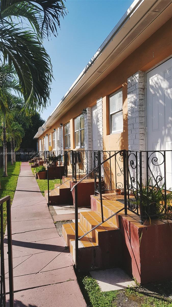 A row of apartment units with tiled stairs and black metal railings along a sidewalk — MIAMI, FL