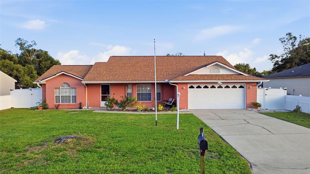 A metal gazebo with curtains sits over a red and tan paver patio in a yard — 2287 BELEN DRIVE, DELTONA, FL