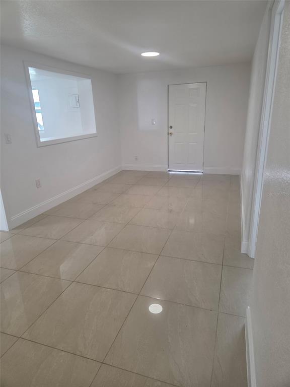 An empty room with white walls, light-colored tile flooring, and a white door — 5930 ALLIGATOR LAKE SHORE W UNIT A2, ST CLOUD, FL