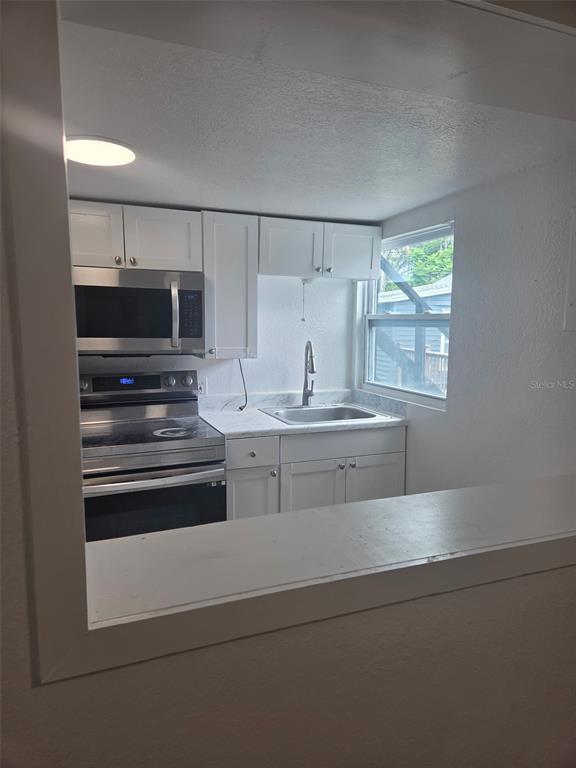 A kitchen with white cabinets, stainless steel appliances, and a window above the sink — 5930 ALLIGATOR LAKE SHORE W UNIT A2, ST CLOUD, FL