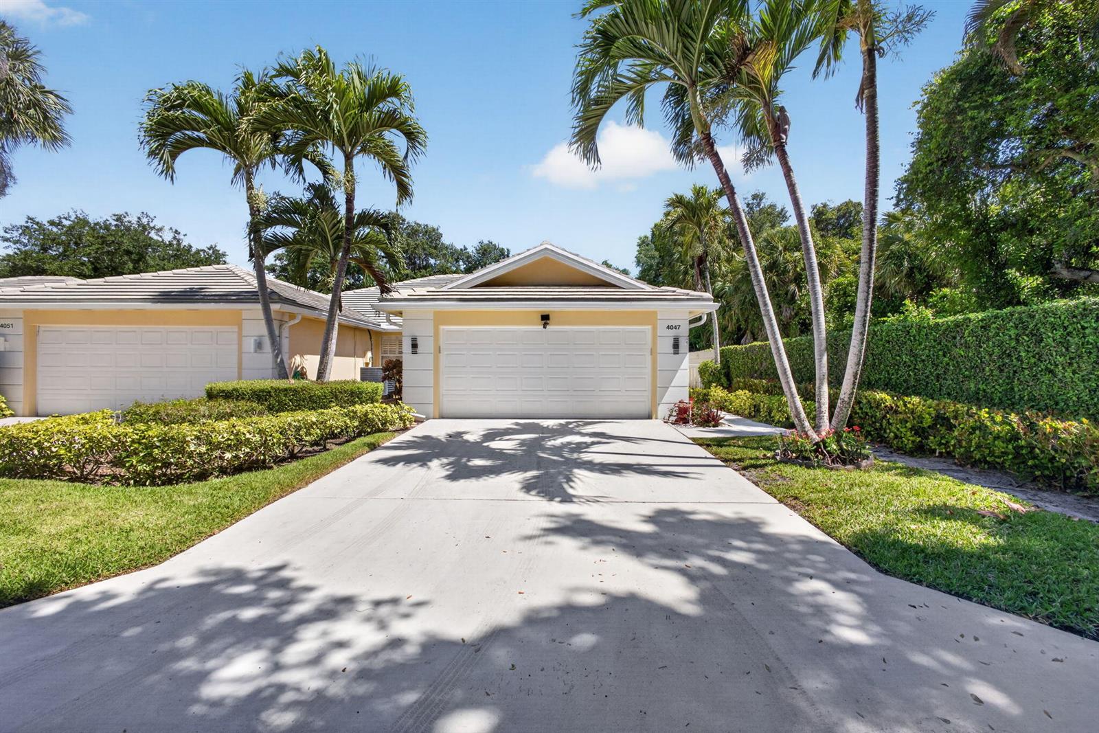 A single-story house with a white garage door, a concrete driveway, and tall palm trees — 4047 Grove Point Road, Palm Beach Gardens FL 33410, PALM BEACH GARDENS, FL