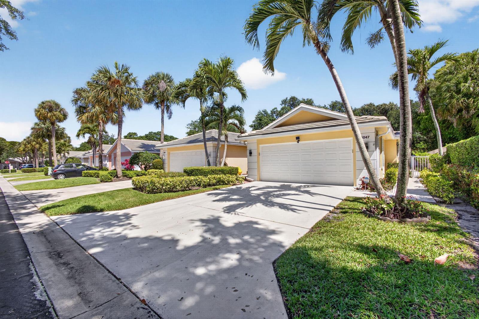 A yellow single-story house with a white garage door and palm trees in the front yard — 4047 Grove Point Road, Palm Beach Gardens FL 33410, PALM BEACH GARDENS, FL