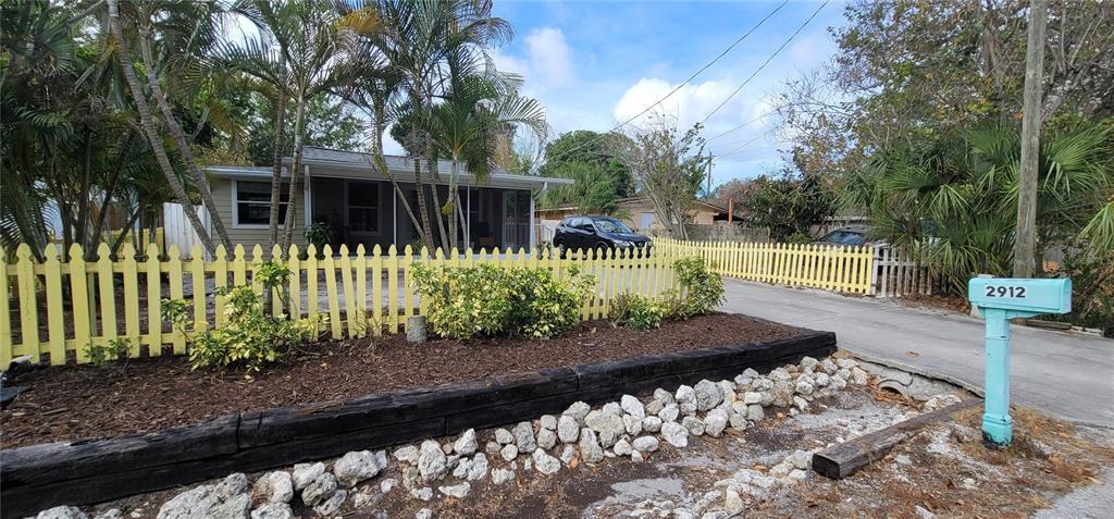 A single-story house with a yellow picket fence and a light blue mailbox — 2912 HAWTHORNE STREET, SARASOTA, FL