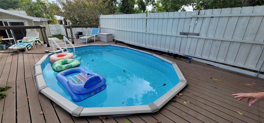 An oval above-ground swimming pool sits on a wooden deck next to a white fence — 2912 HAWTHORNE STREET, SARASOTA, FL