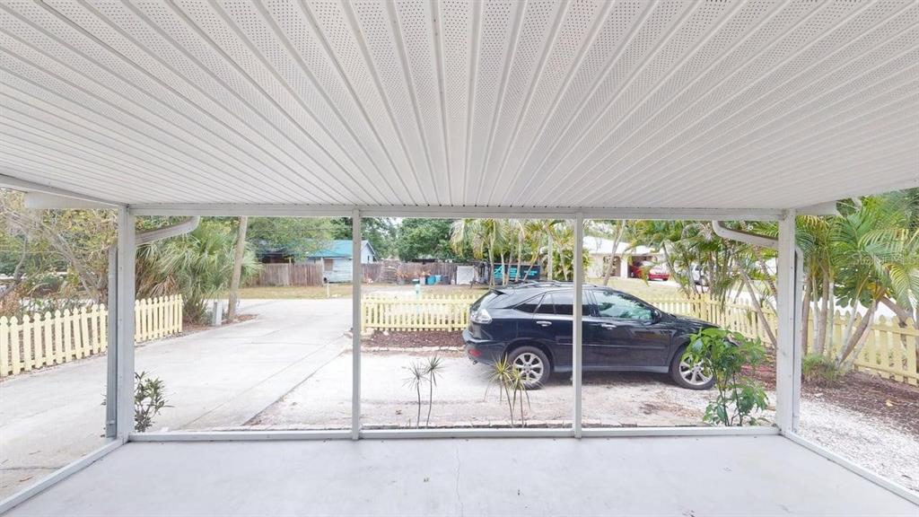 A view from a screened-in porch looking out at a driveway, a car, and fencing — 2912 HAWTHORNE STREET, SARASOTA, FL