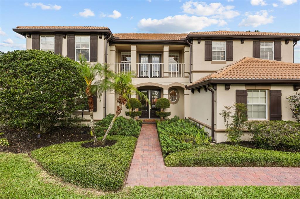 A two-story house with a tiled roof, beige stucco exterior, and a brick walkway entrance — 5674 BASSETT PLACE, SANFORD, FL