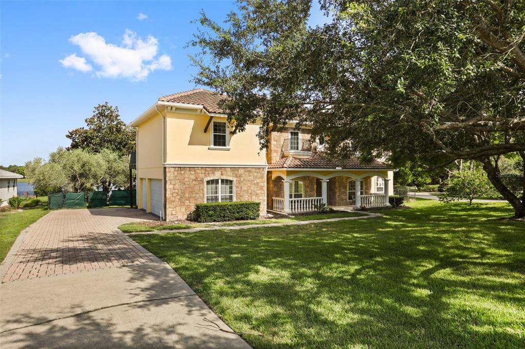 A two-story house with a stone and stucco exterior, a tiled roof, and a paved driveway — 5554 PALM LAKE CIRCLE, ORLANDO, FL