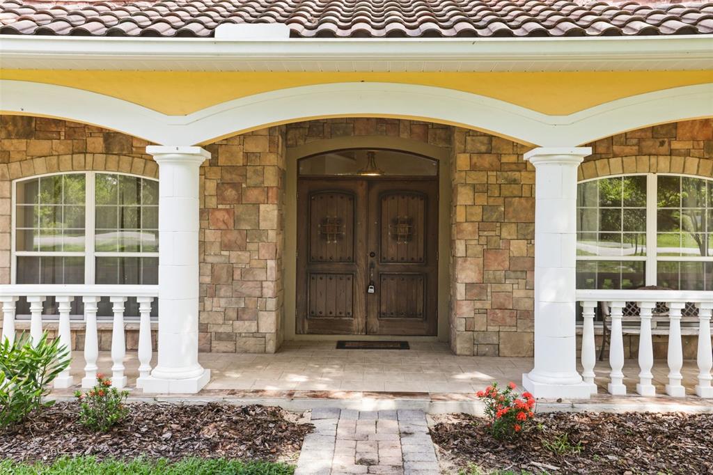 A stone-faced house entrance features a covered porch, white columns, and double wooden doors — 5554 PALM LAKE CIRCLE, ORLANDO, FL