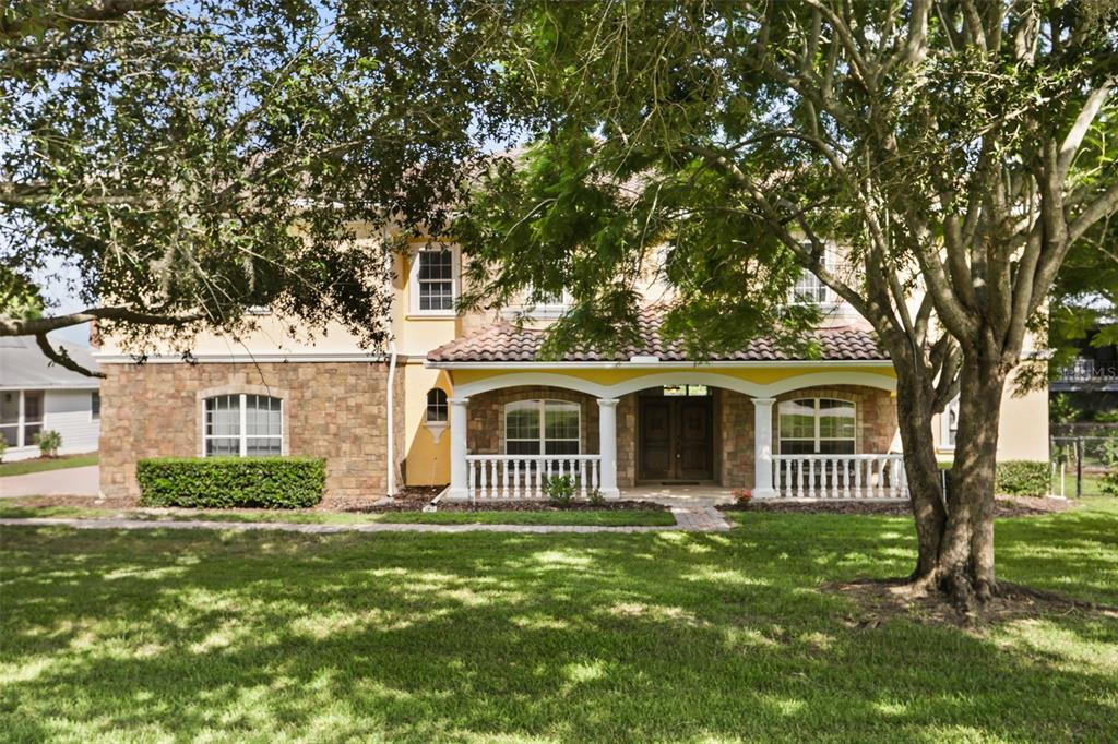 A two-story house with a stone facade, yellow stucco, and a covered front porch — 5554 PALM LAKE CIRCLE, ORLANDO, FL