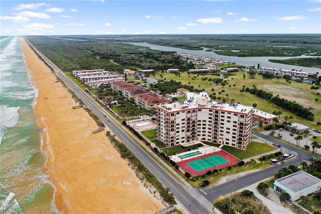 An aerial view of a beachfront condominium complex with a tennis court and coastal landscape — 3600 OCEAN SHORE BOULEVARD UNIT 311, FLAGLER BEACH, FL