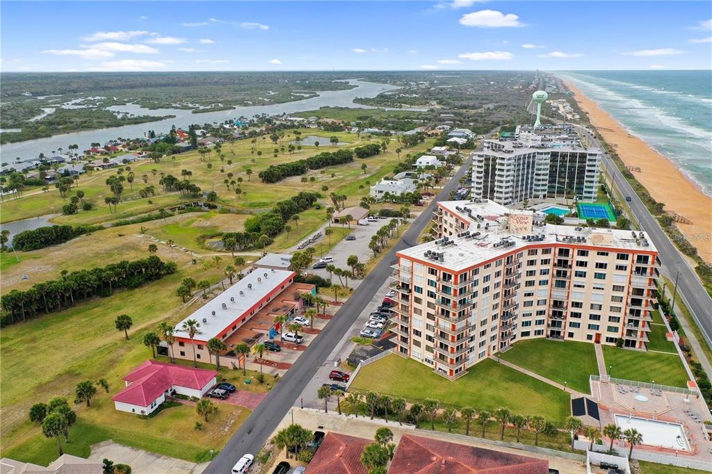An aerial view shows a coastal area with high-rise condominiums, a golf course, and beach — 3600 OCEAN SHORE BOULEVARD UNIT 311, FLAGLER BEACH, FL