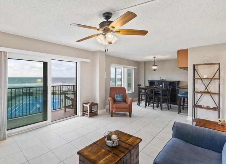 A living and dining area with tile floors, a ceiling fan, and a balcony overlooking tennis courts — 3600 OCEAN SHORE BOULEVARD UNIT 311, FLAGLER BEACH, FL