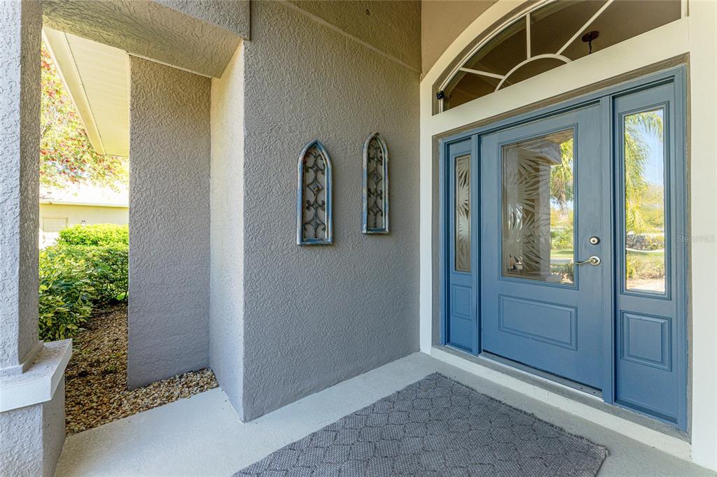 A blue front door with glass panels and a transom window sits under a covered entryway — 872 CLEAR LAKE DRIVE, ENGLEWOOD, FL