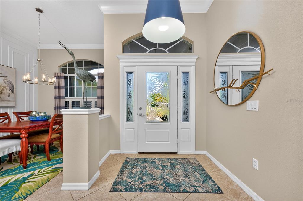 An entryway features a white front door with glass panels, tile flooring, and a round mirror — 872 CLEAR LAKE DRIVE, ENGLEWOOD, FL