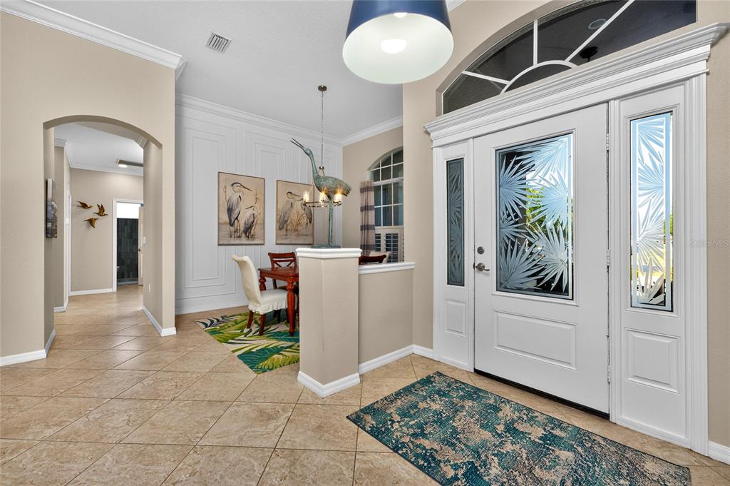 An entryway with tile flooring, a white front door with glass inserts, and a dining area — 872 CLEAR LAKE DRIVE, ENGLEWOOD, FL