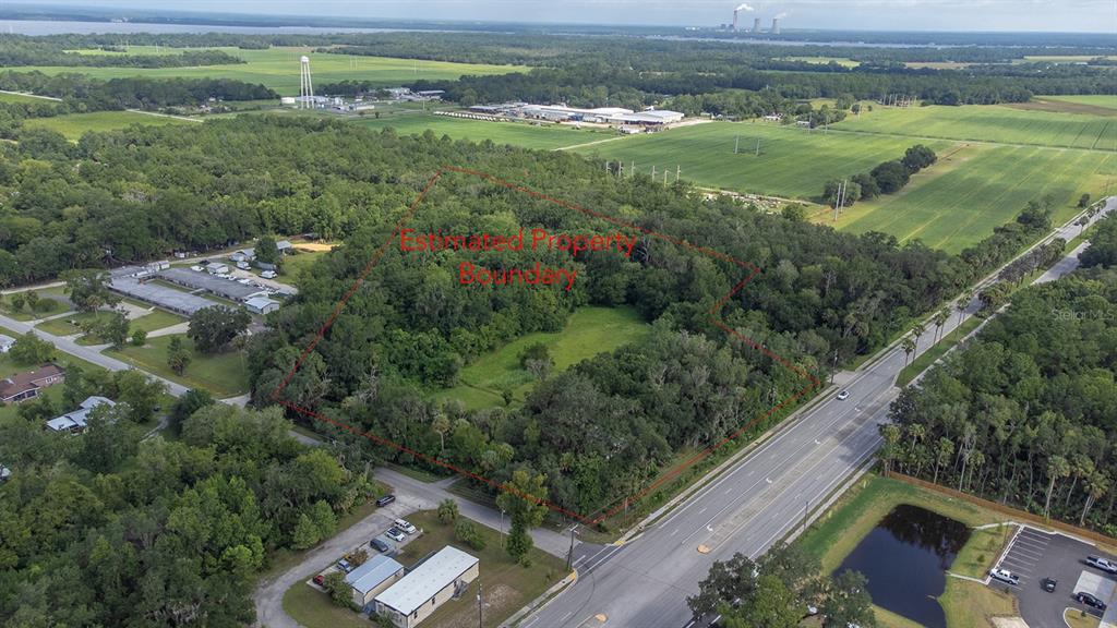 An aerial view shows a wooded plot of land outlined in red next to a highway — 104 W LOUIS BROER ROAD, EAST PALATKA, FL