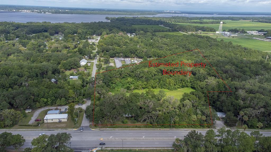 An aerial view shows a wooded lot outlined in red along a multi-lane road — 104 W LOUIS BROER ROAD, EAST PALATKA, FL