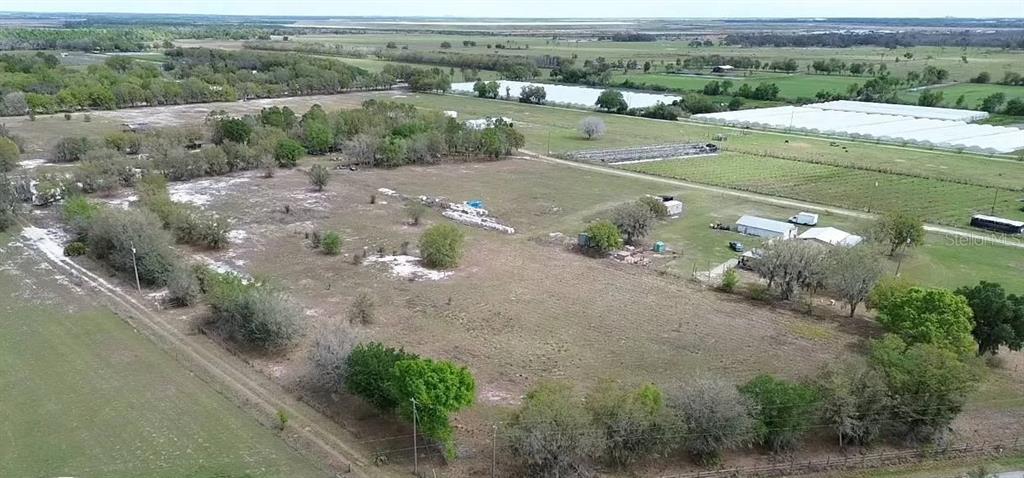 An aerial view shows a large, grassy rural property with scattered trees and small buildings — 30620 TAYLOR GRADE ROAD, DUETTE, FL