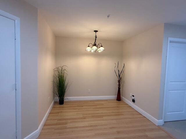 An empty dining area features light wood flooring, beige walls, and a hanging chandelier — 1945 S Ocean Drive # 509, Hallandale Beach FL 33009, HALLANDALE BEACH, FL