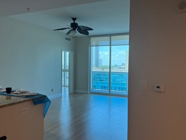 An interior view of a living area with light wood floors, a ceiling fan, and balcony — 1945 S Ocean Drive # 509, Hallandale Beach FL 33009, HALLANDALE BEACH, FL