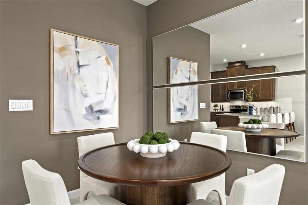 A dining area features a round wooden table, white chairs, wall art, and large mirrors — 9868 WALKWAY DRIVE, ORLANDO, FL