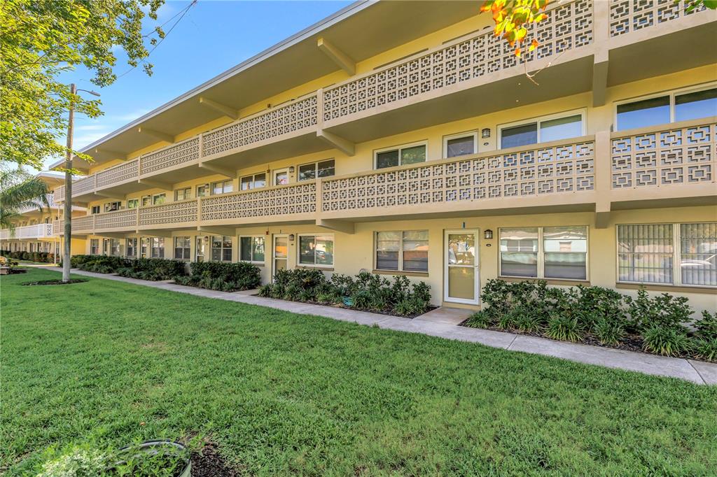 A three-story apartment building with yellow walls and decorative concrete block balcony railings — 1051 79TH AVENUE N UNIT 105, ST PETERSBURG, FL