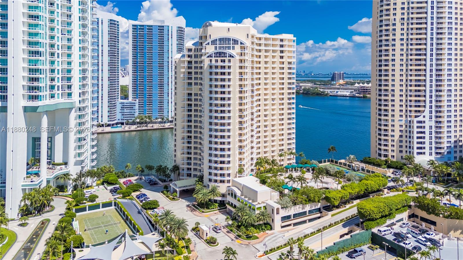 An aerial view shows high-rise residential buildings, a waterway, and landscaped grounds with tennis courts — 888 Brickell Key Dr # 1807, Miami FL 33131, MIAMI, FL