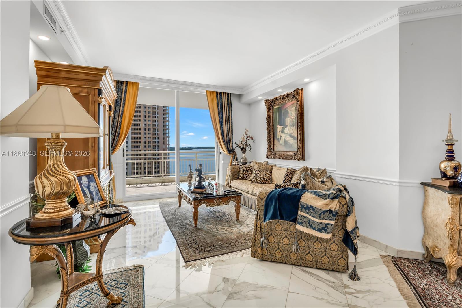 A living room features marble floors, ornate furniture, a large framed painting, and balcony views — 888 Brickell Key Dr # 1807, Miami FL 33131, MIAMI, FL