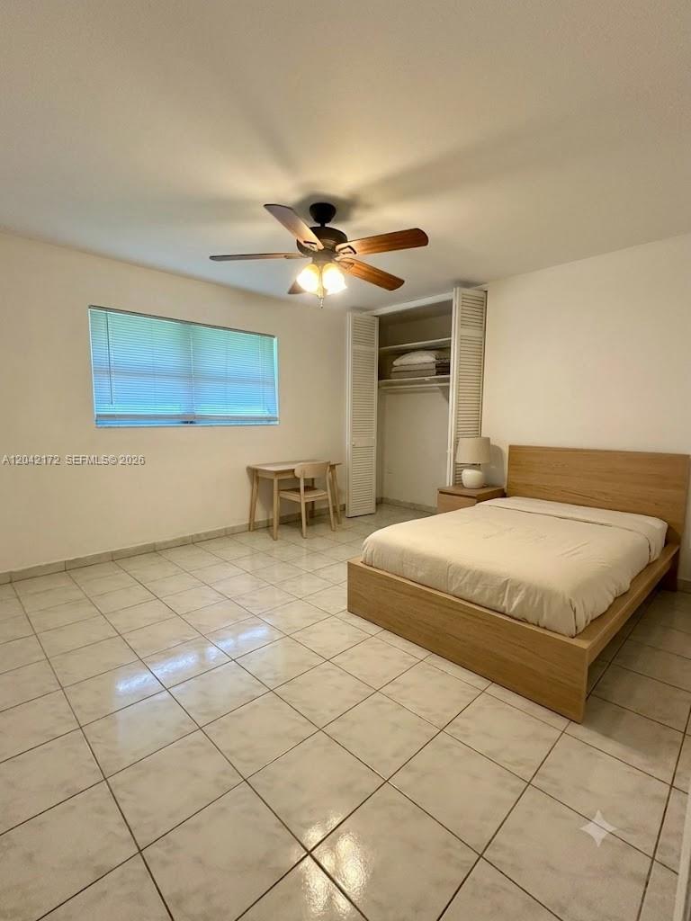 A bedroom features a light wood bed frame, a small desk, and tiled flooring — 2230 Jackson St # 1W, Hollywood FL 33020, HOLLYWOOD, FL