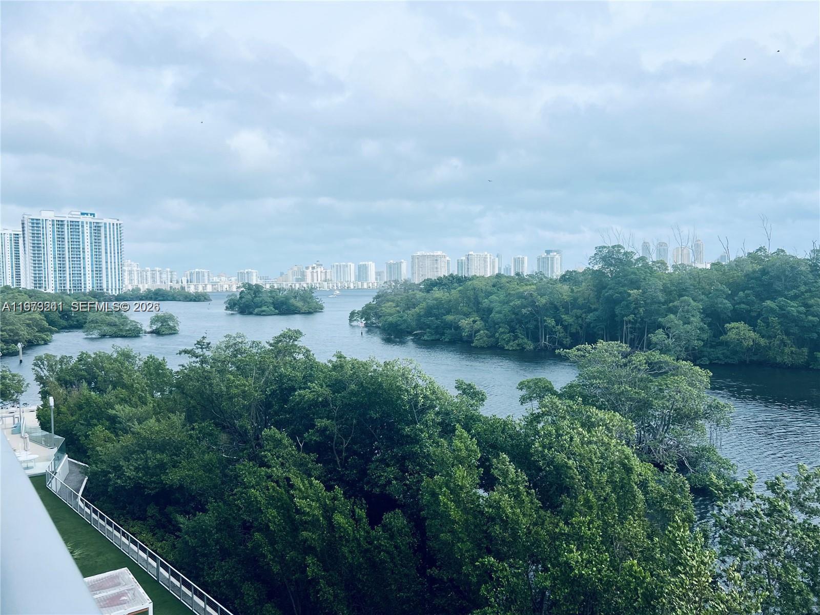 An elevated view shows a waterway surrounded by dense trees with city buildings in distance — 16385 Biscayne Blvd # 421, North Miami Beach FL 33160, NORTH MIAMI BEACH, FL