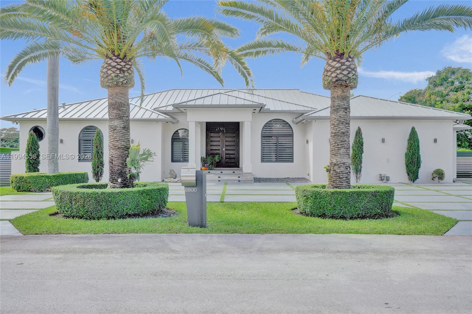 A single-story white house features a metal roof, arched windows, and two prominent palm trees — 2600 SW 128th Ct, Miami FL 33175, MIAMI, FL