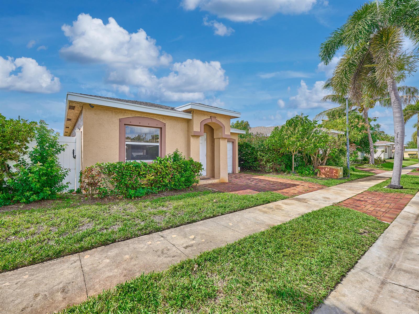 A single-story tan stucco house features a brick driveway and a sidewalk in front — 556 E Ridge Cir Circle N, Boynton Beach FL 33435, BOYNTON BEACH, FL
