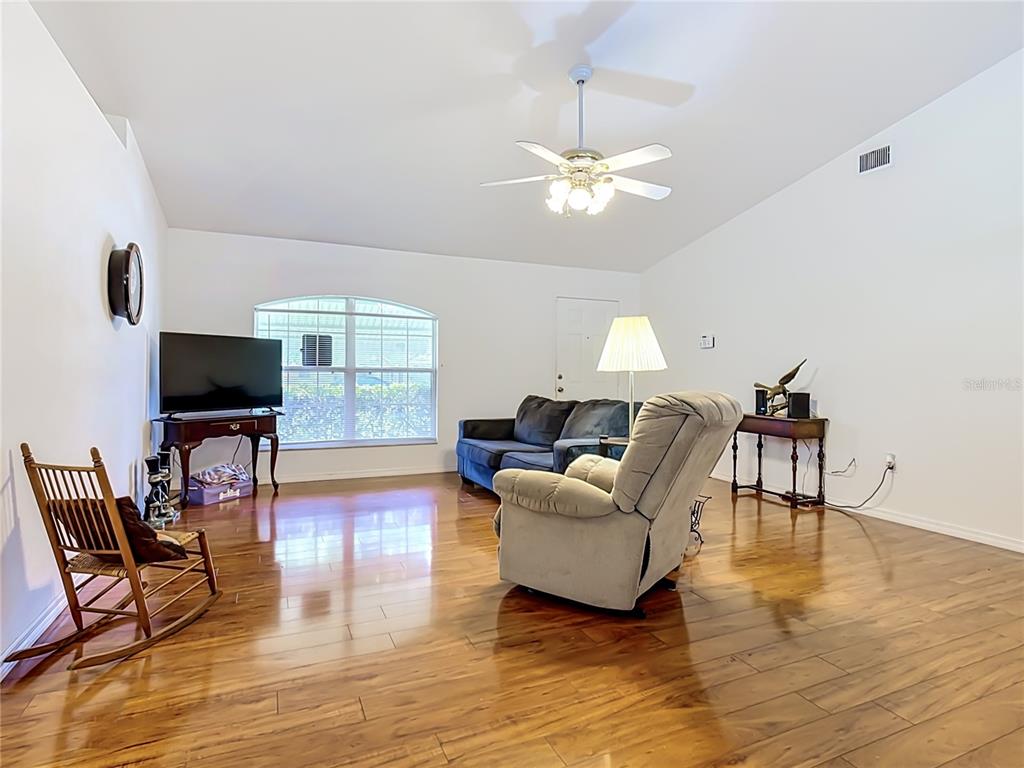 A living room features hardwood floors, a ceiling fan, a television, and assorted furniture — 517 ILLINOIS AVENUE, ST CLOUD, FL