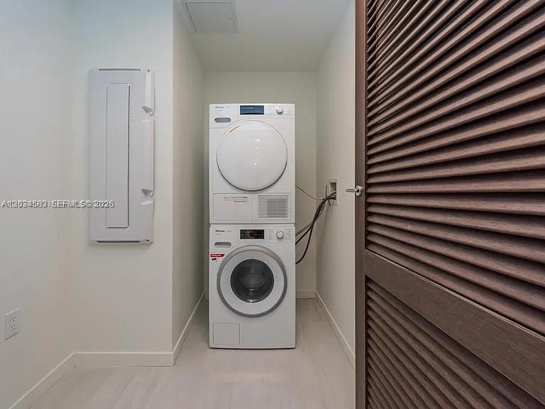 A laundry closet features a stacked washer and dryer unit next to a louvered door — 1000 Brickell Plz # 3509, Miami FL 33131, MIAMI, FL