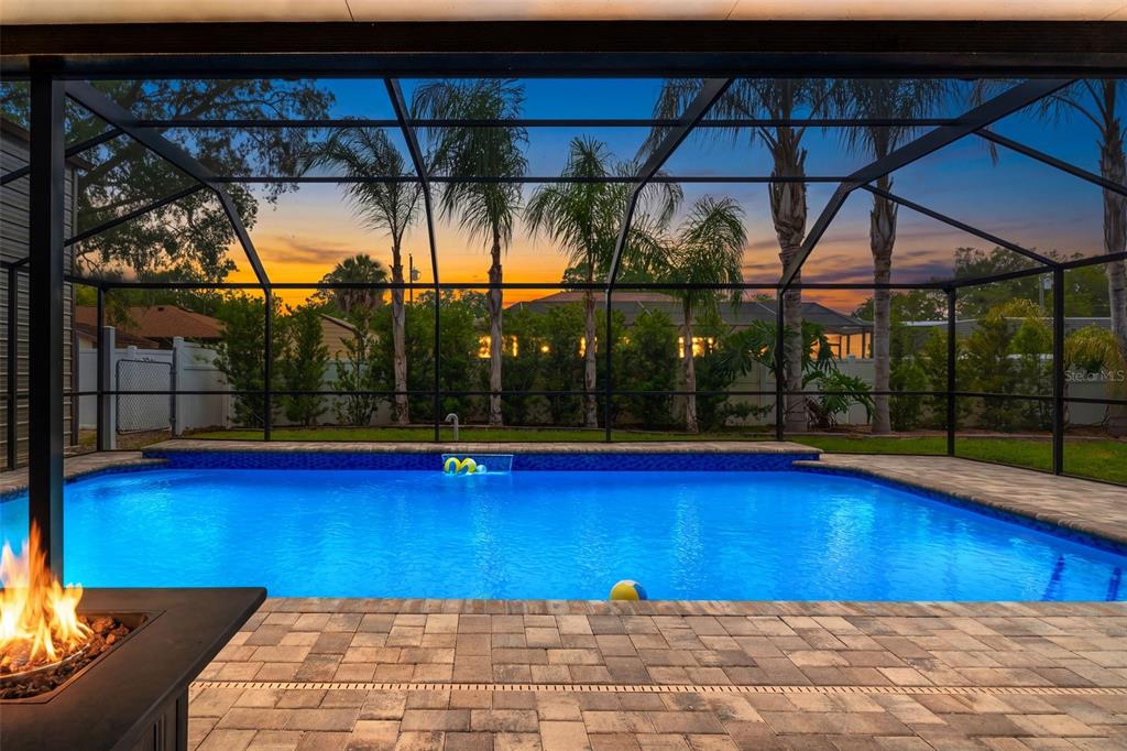 A swimming pool with a screen enclosure and a fire pit on a paved patio — 2451 DELTONA BOULEVARD, SPRING HILL, FL