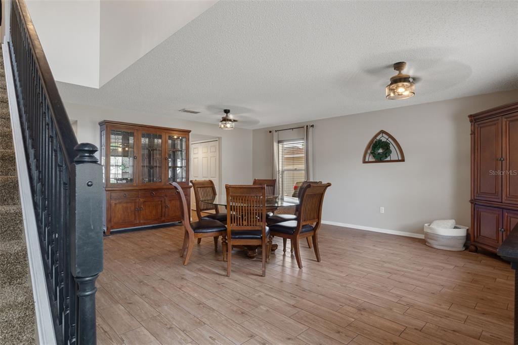 A dining room features wood-look tile flooring, a wooden hutch, and a glass-topped table — 2451 DELTONA BOULEVARD, SPRING HILL, FL