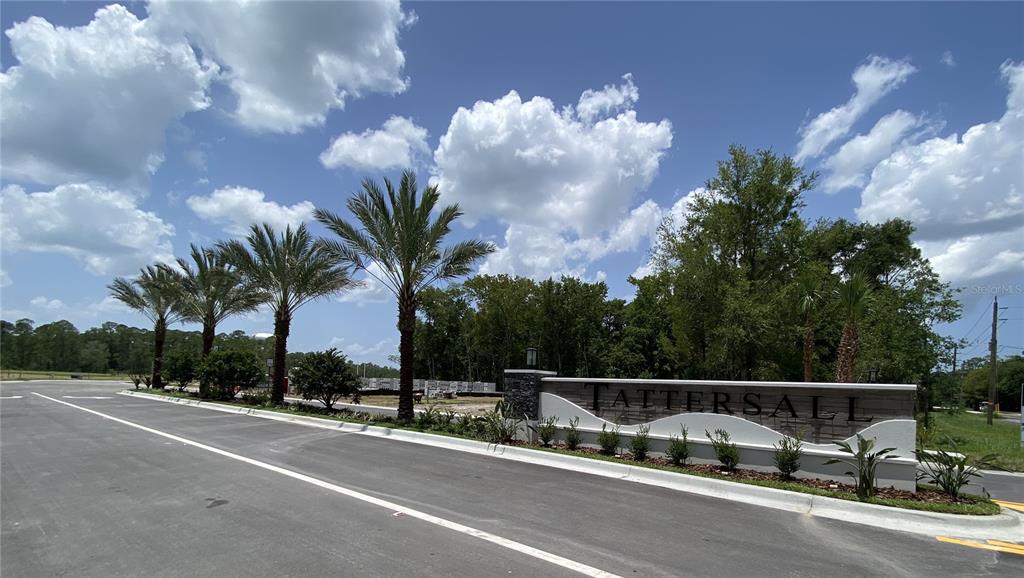 A stone monument sign for Tattersall stands beside a road lined with palm trees — 62 LITTLE LYNN LOOP, ORMOND BEACH, FLORIDA, FL