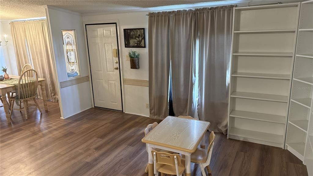 A dining area and living space feature wood-look flooring, white walls, and a small table — 6344 BASS HIGHWAY, ST CLOUD, FL